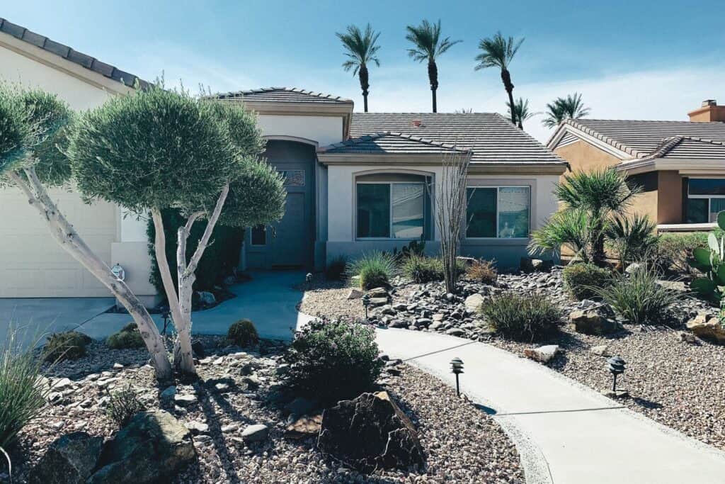 A no grass front yard landscaped with gravel beds, desert plants, and a stone walkway