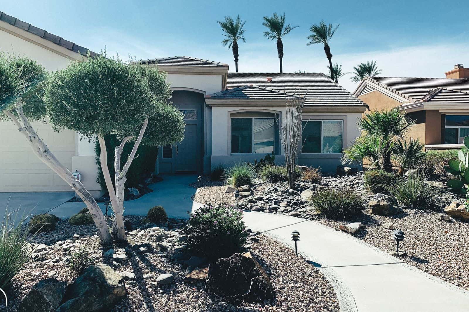 A no grass front yard landscaped with gravel beds, desert plants, and a stone walkway
